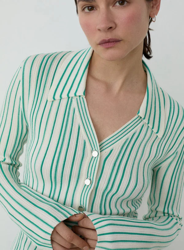 Woman wearing a green and white striped shirt against a plain background