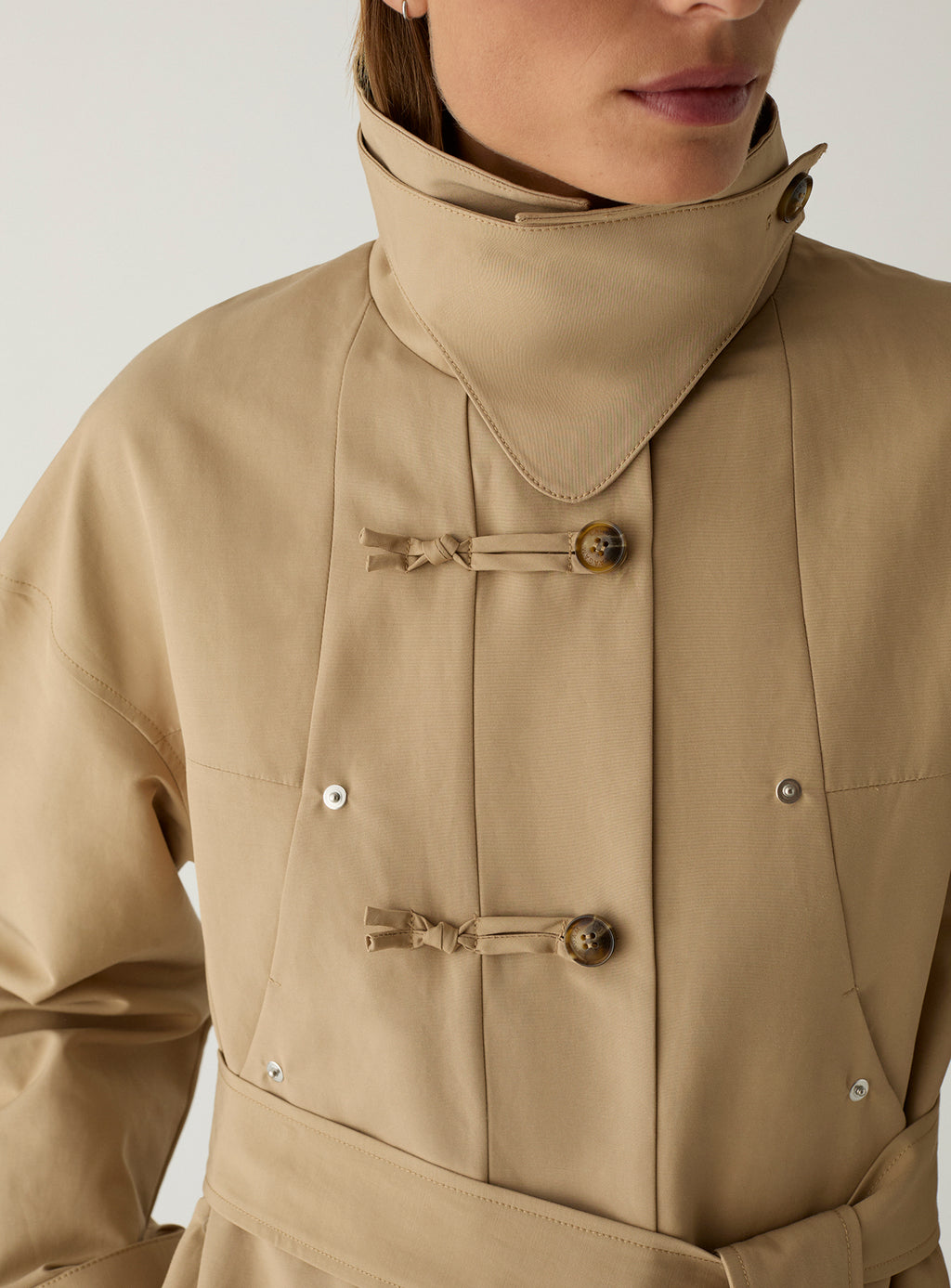Close-up of the LAAGAM Antwerp camel trench with the collar standing, showing the knotted toggle fastenings and press studs.