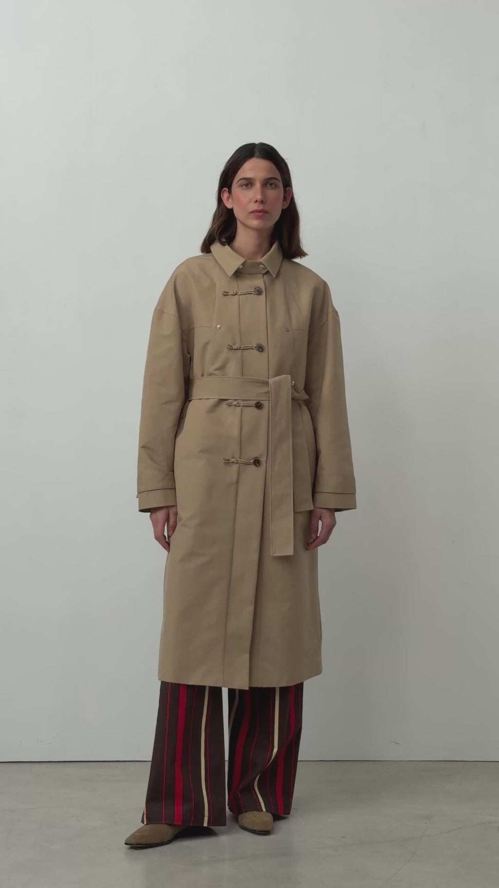 Video of the camel Antwerp trench coat by LAAGAM, shown on a model from the front and back.